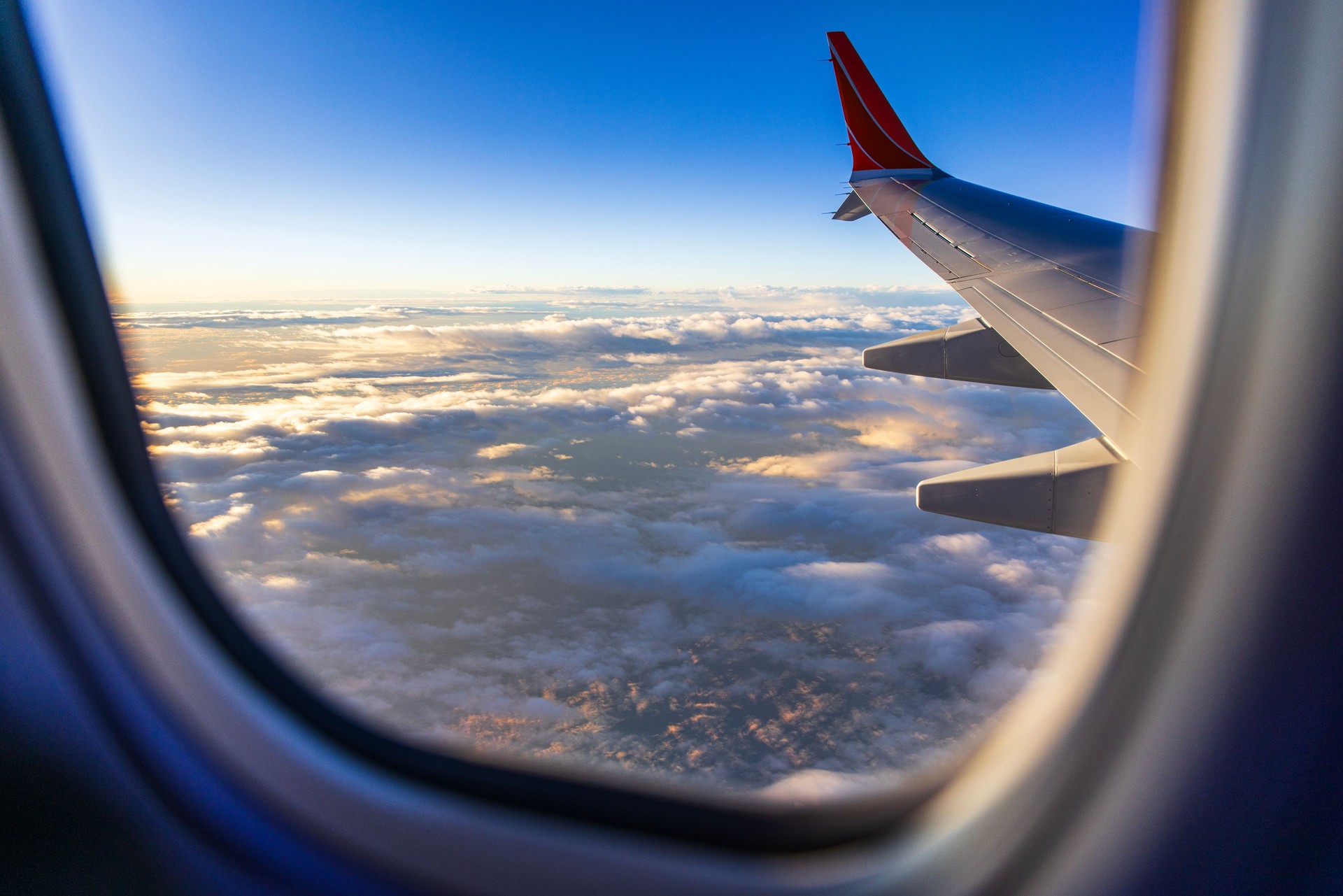 Looking out window of aircraft while flying above the clouds
